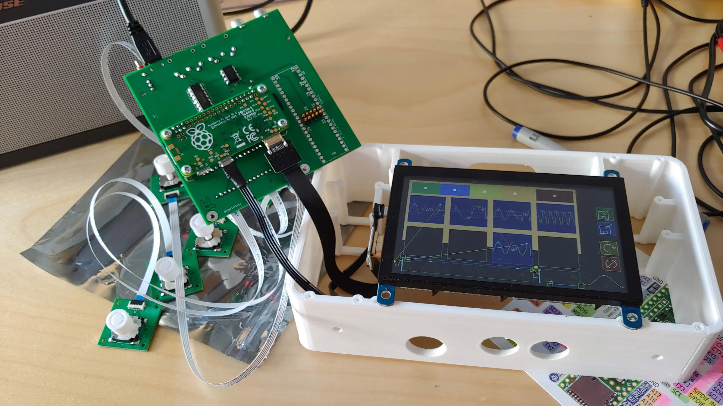 An early FIRST LOVE prototype with exposed circuit boards, rotary controls and a touchscreen on a workshop table.